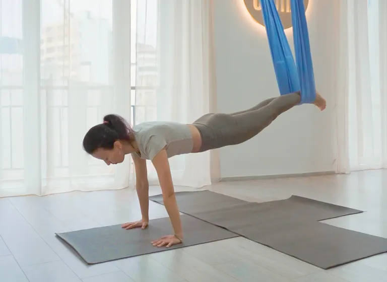Занятие по направлению «Fly fitness» в студии «Место Силы» в Батуми: преподаватель Оксана Алендукова демонстрирует выполнение планки в воздухе с использованием подвесного гамака для опоры стоп